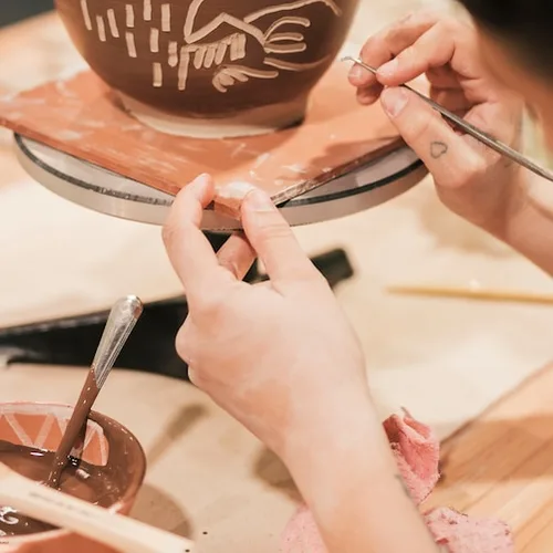 Hands carving the rim of a bowl