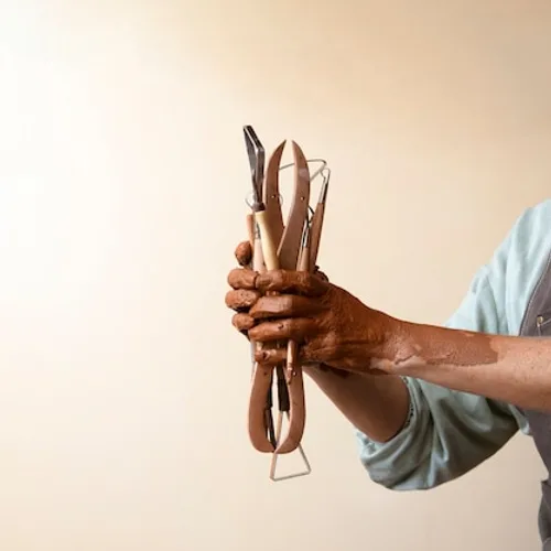 A craftsperson holding pottery tools